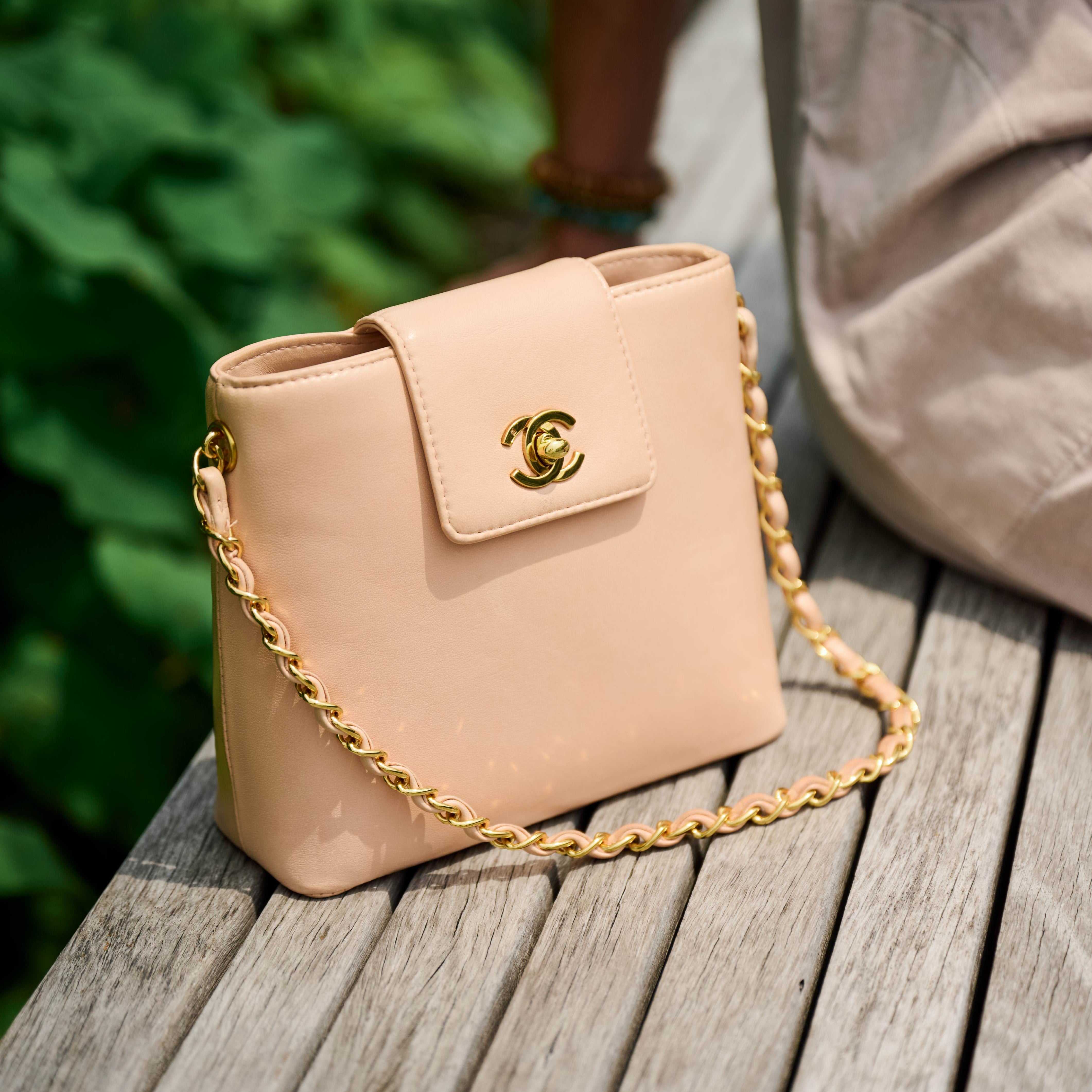 Chanel blush shoulder bag with 24k gold chain on a wooden surface
