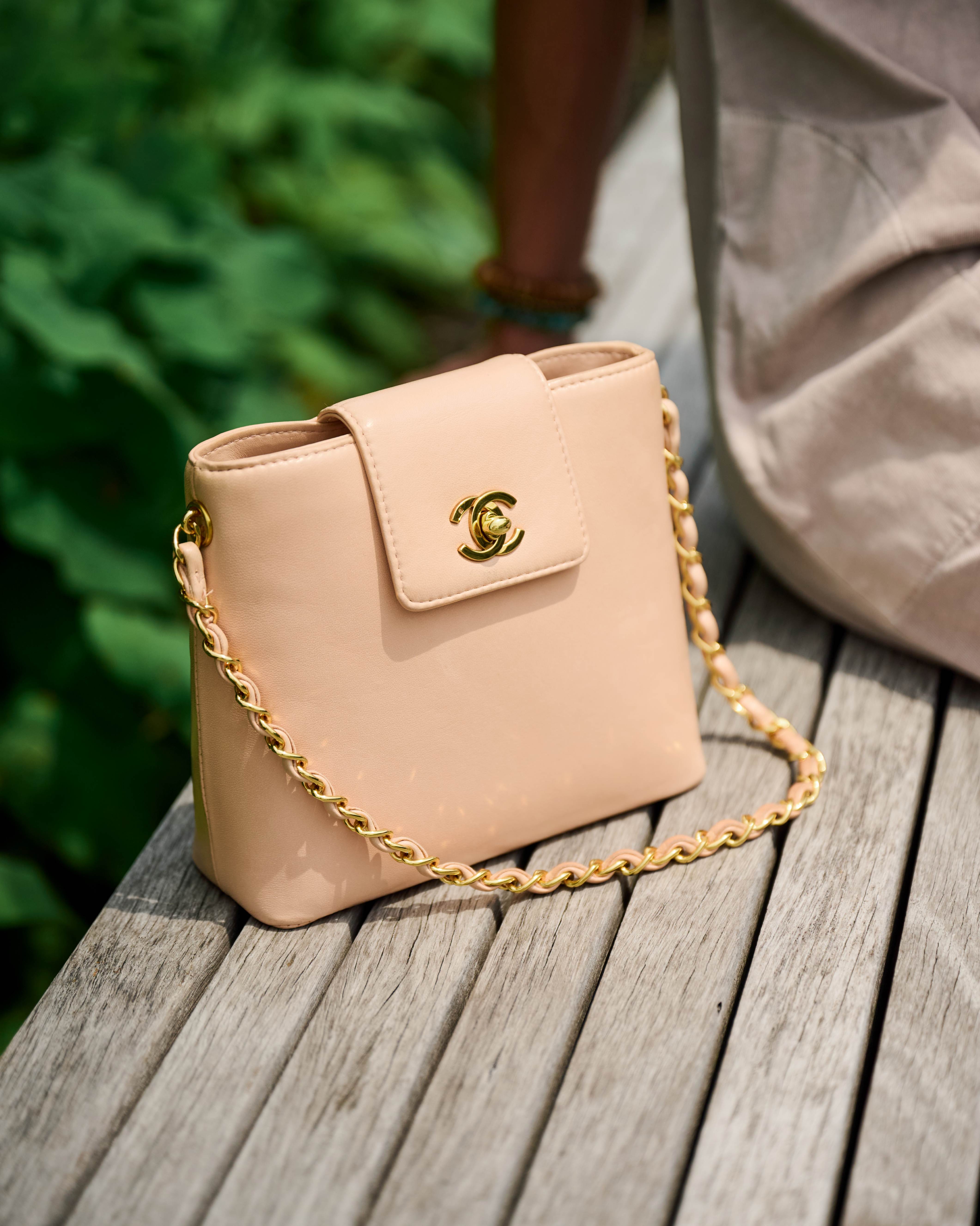 Chanel blush shoulder bag with 24k gold chain on a wooden surface